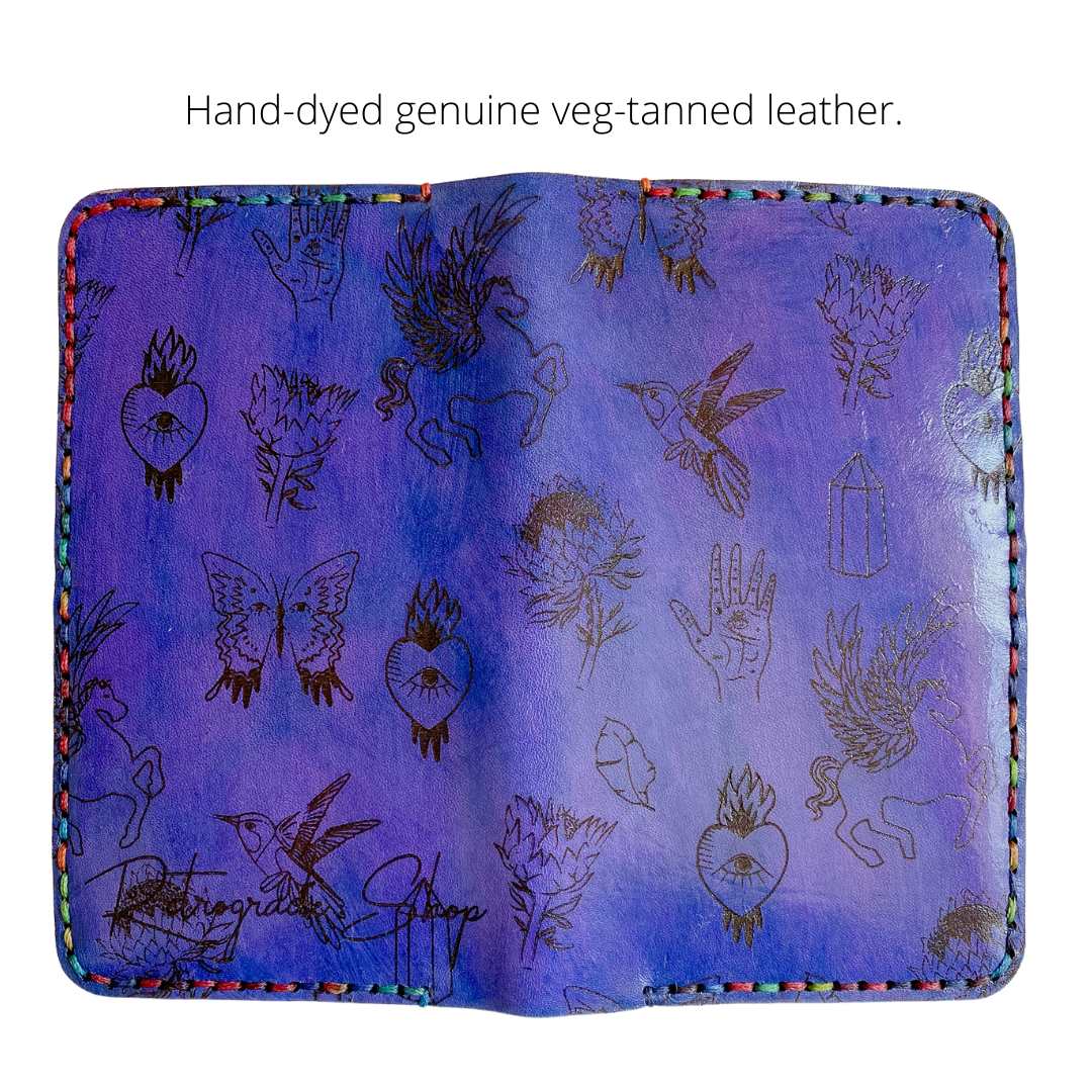 Photo of a purple leather wallet with celestial designs and rainbow stitching on white background