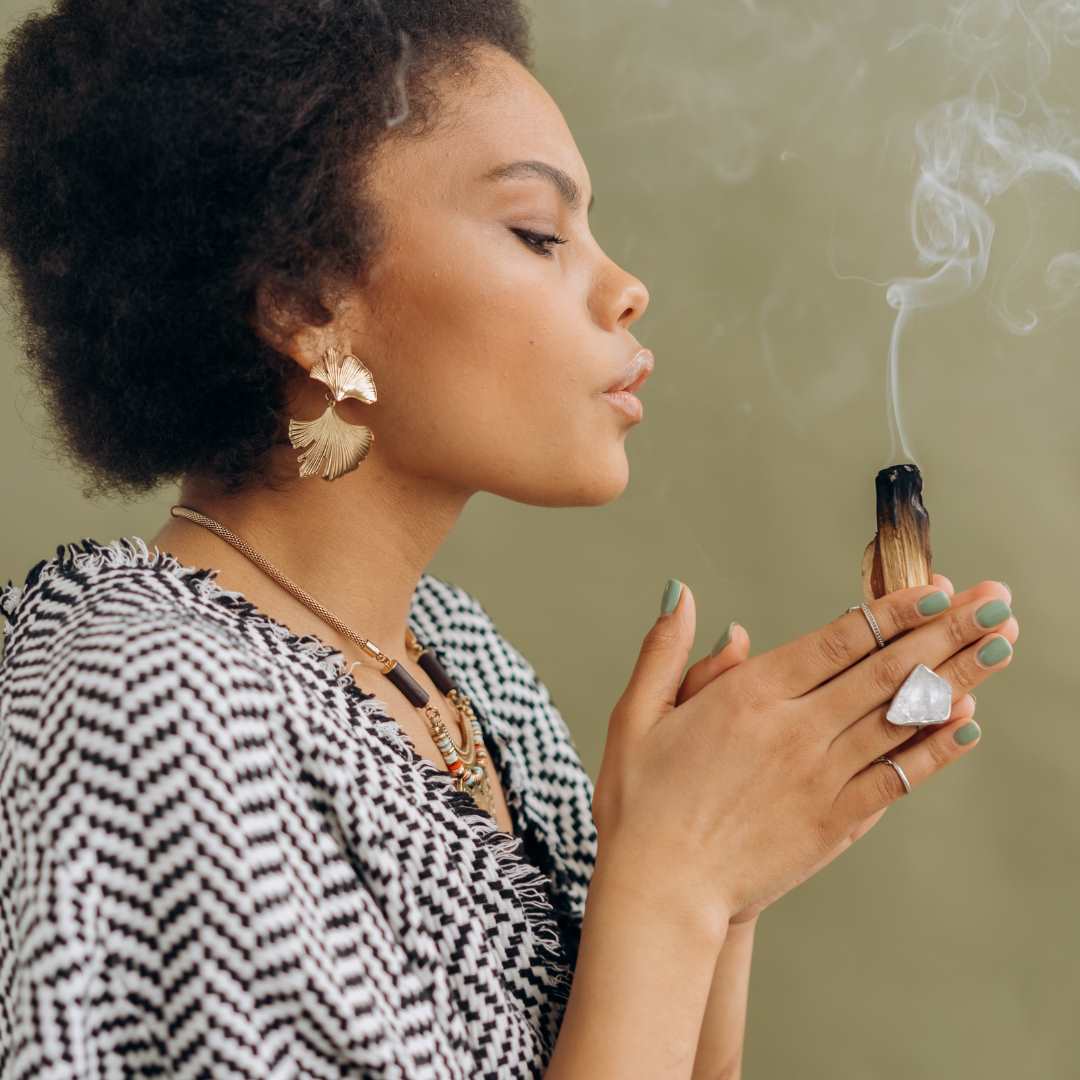 Image of a woman blowing palo santo smoke 