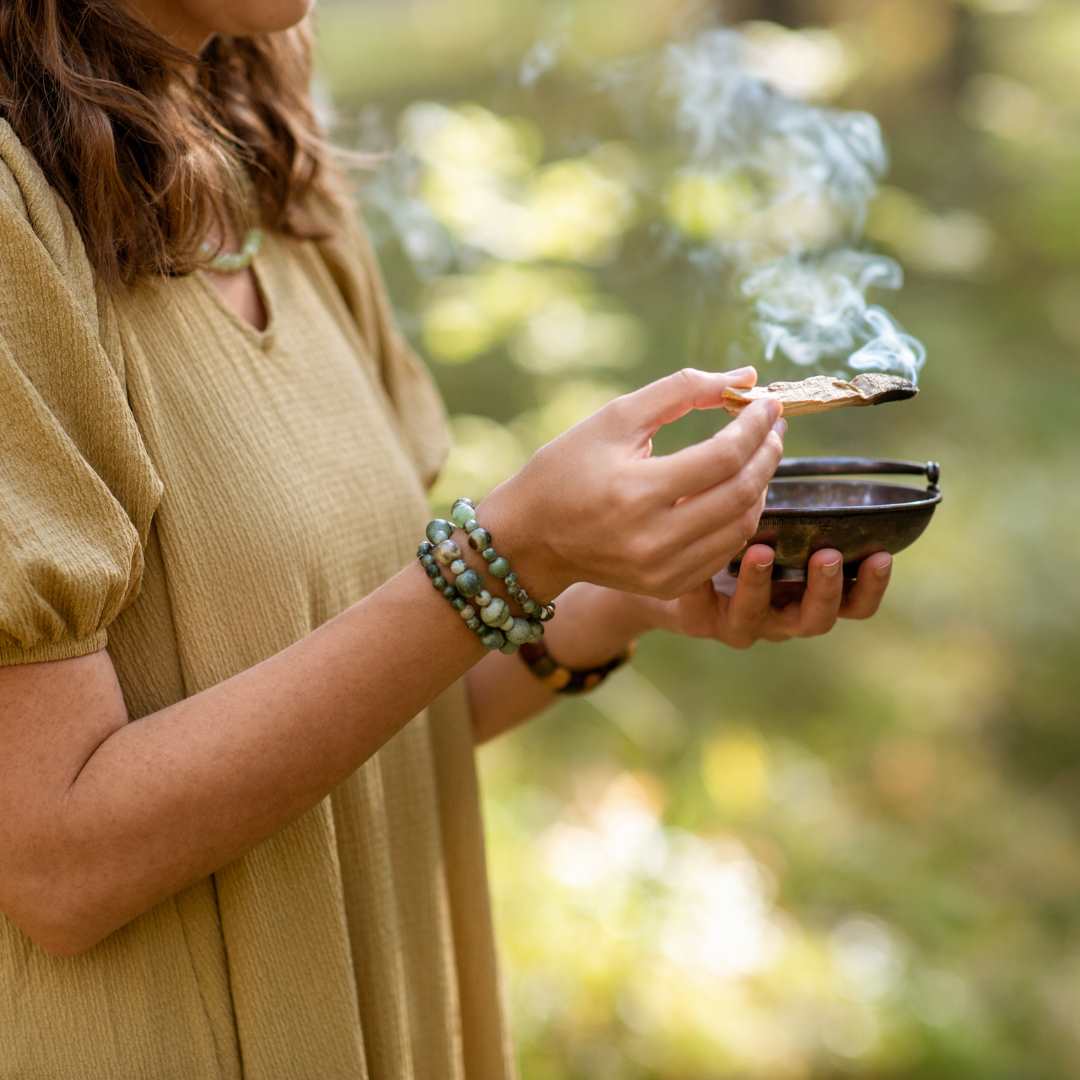 Woman holding a smuldering palo santo stick in nature image