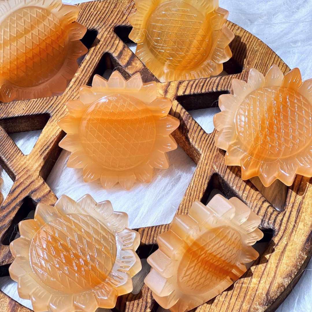 Multiple Orange Calcite Sunflower Crystals laying on wood image