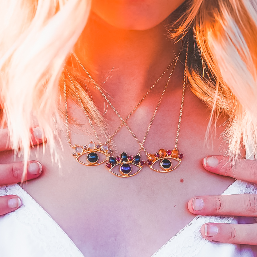 Image of female model wearing three gold evil eye necklaces by The Retrograde Shop