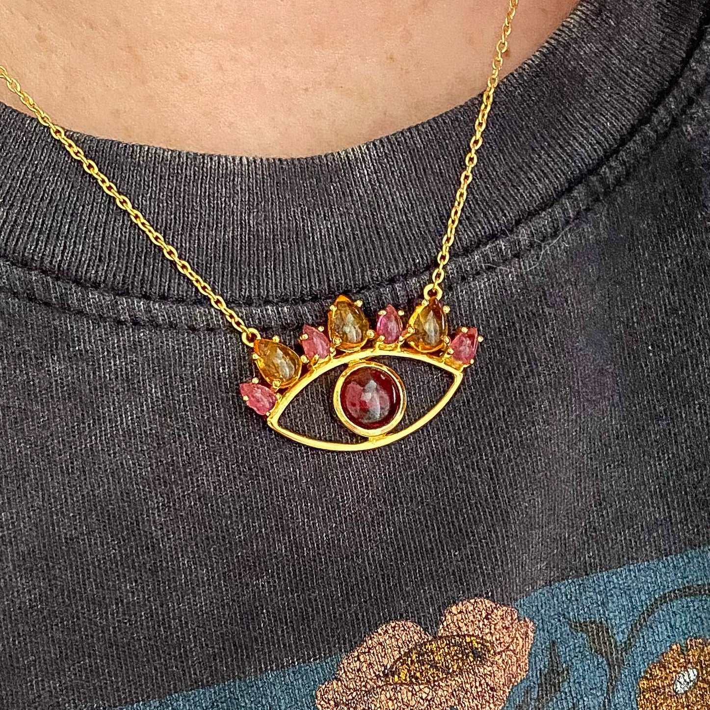Lifestyle photo of evil eye necklace with garnet, pink tourmaline and spessarite gemstones